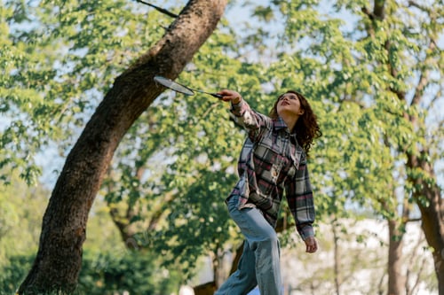 Preview: outdoors in a park with trees against the backdrop of surrender a young brunette girl hits serve