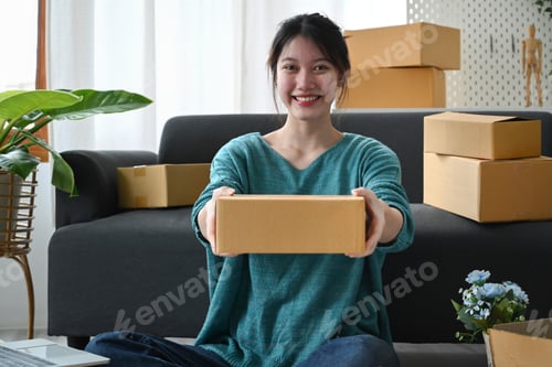Preview: Startup small business entrepreneur holding parcel boxes of product and smiling to camera.