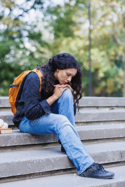 Preview: Young student feeling sad and sitting alone on stairs