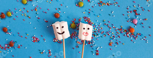 Preview: marshmallows on wooden skewers with color sweets on blue background.