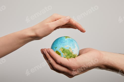 Preview: man and woman holding planet model on grey background, earth day concept