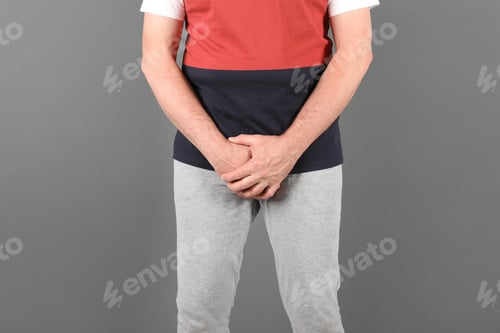 Preview: Mature man with urological problems suffering from pain on grey background