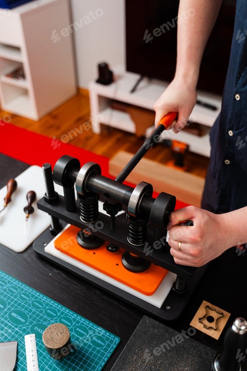 Preview: Craftsman embosses leather with press machine. Handmade accessories gain premium finish