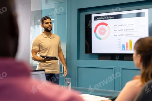 Preview: Holding tablet and explaining charts, man presenting department budgets in meeting room