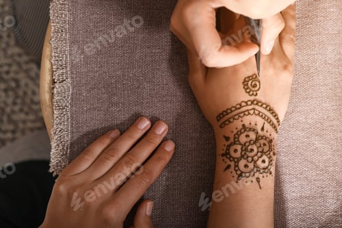 Preview: Master making henna tattoo on hand, top view. Traditional mehndi
