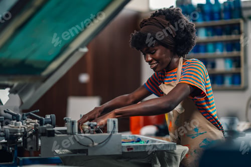 Preview: Happy diverse graphic worker pressing ink with squeegee at printing shop