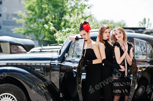 Preview: Three young girl in retro style dress near old classic vintage cars.