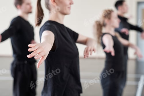 Preview: Hand of young active woman in black t-shirt exercising at lesson in dance studio