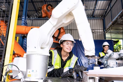 Preview: Young female asian service engineer holding robot controller operate robot arm automation factory