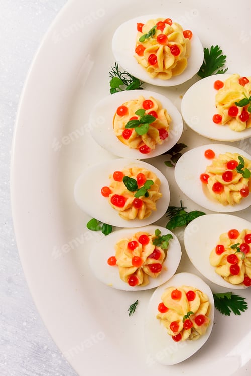Preview: Stuffed eggs, with red caviar, micro greenery, Snack, on a white plate, top view,