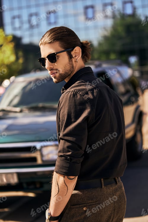Preview: vertical shot of eye catching man with ponytail and accessories posing near his car, sexy driver