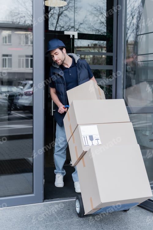 Preview: Courier holding car with boxes near open door of building outdoors