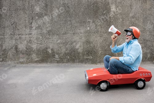 Preview: Funny businessman driving retro pedal car outdoor