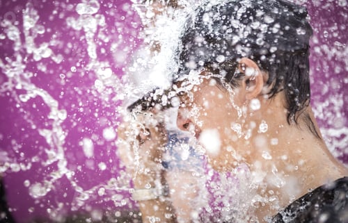 Preview: A young man standing in drops of water spray.
