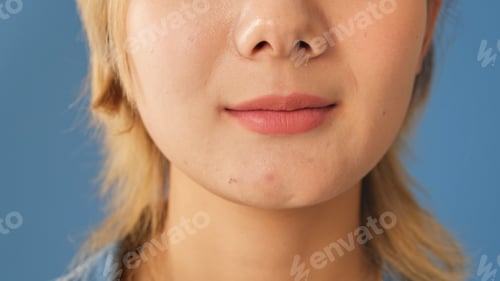 Preview: Detailed close-up shot of young woman's lips, isolated on blue background