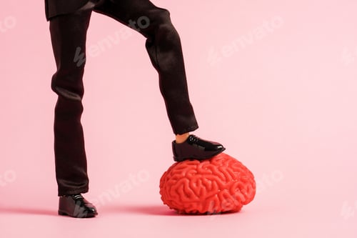 Preview: Male feet trample the human brain model on a pink background. Hack the brain concept.
