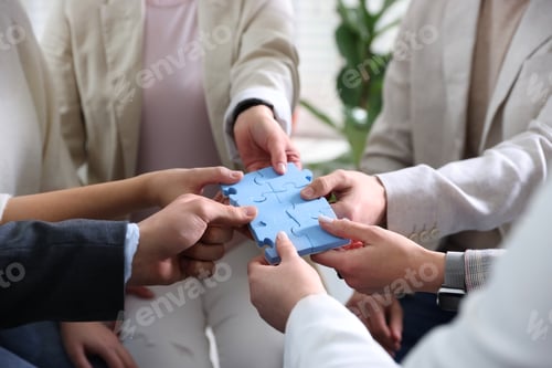 Preview: Unity concept. People putting puzzle pieces together indoors, closeup