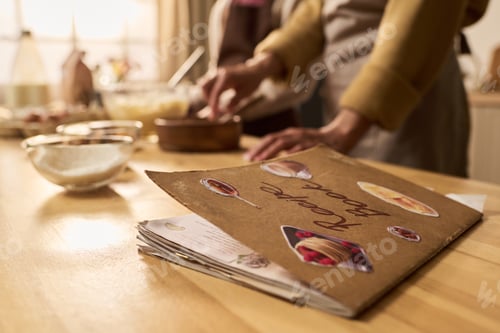 Preview: Middle Aged Woman Preparing Ingredients While Using Recipe Book