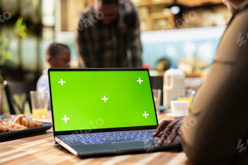 Preview: Green screen laptop next to parents and kids sharing breakfast in the kitchen