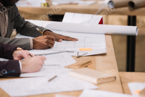 Preview: cropped shot of architects drawing building plans together at office
