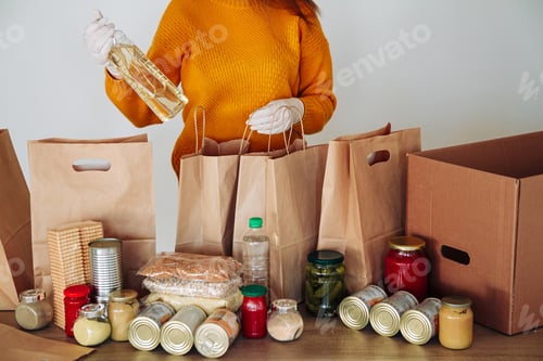 Preview: woman in medical gloves packing food for donation