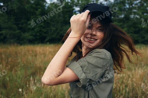 Preview: woman straightens her cap on her head and green shirt nature fresh air