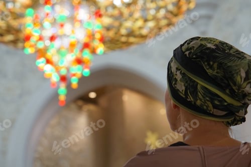 Preview: Woman looking at the chandelier lights at the mosque