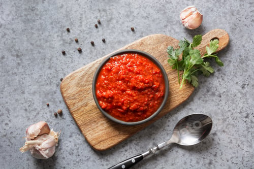 Preview: Tasty ajvar. Vegetable sauce or caviar of baked red bell pepper on grey. Balkan cuisine.