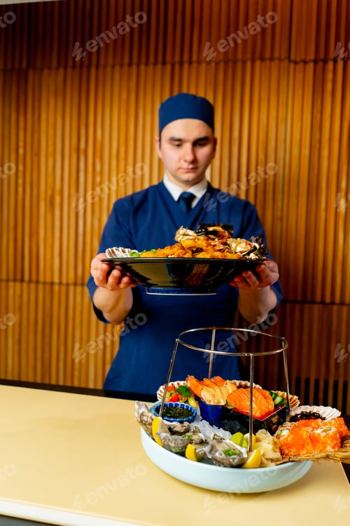 Preview: in a Japanese restaurant chef in blue prepares an expensive plate of seafood
