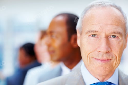 Preview: Serious senior executive with team behind him. Closeup of senior Business man with team behind him.