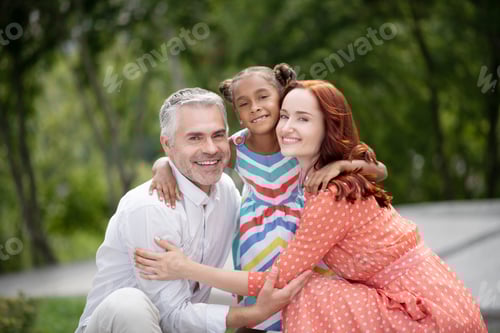 Preview: Loving foster parents hugging their lovely dark-skinned girl