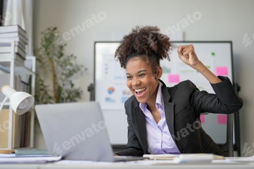 Preview: Young office worker is raising her fist in the air, excited about a win she just had