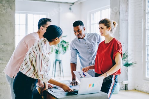 Preview: Multiethnic team having discussion about work with laptop and documents at office