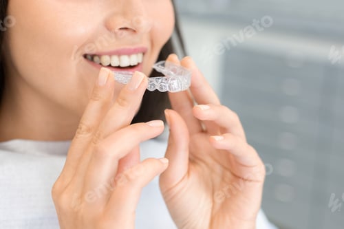 Preview: Girl holding invisible braces, moder teeth trainer