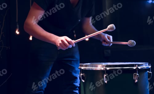 Preview: The drummer plays with mallets on floor tom in dark room.