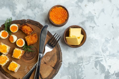 Preview: top view tasty caviar sandwiches with boiled eggs and cutlery on wooden board white background