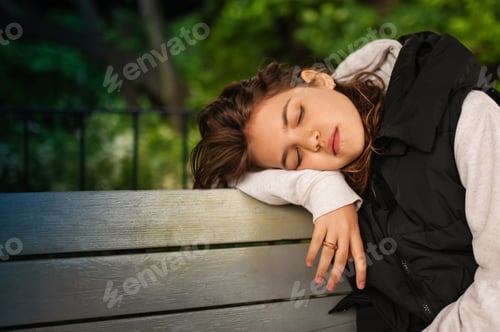 Preview: Tired woman sleeping on wooden bench outdoors