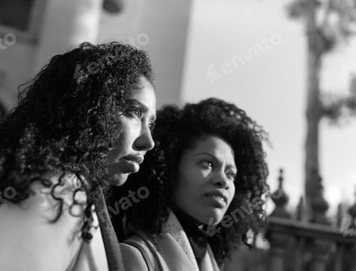 Preview: Side portrait of two female friends looking away outdoors.
