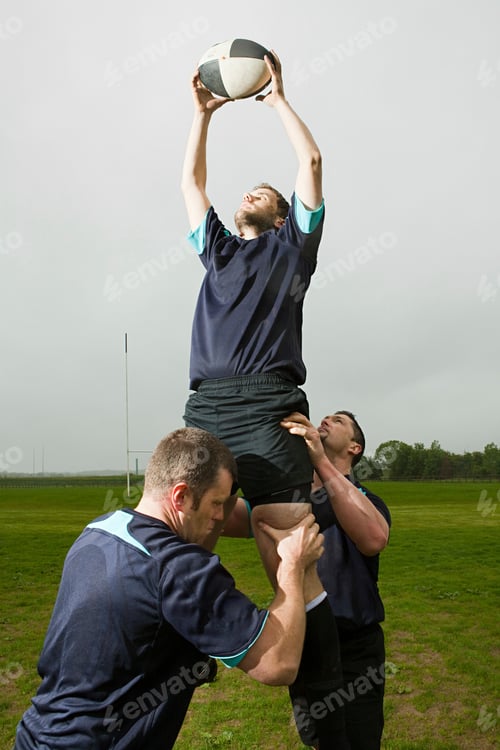Preview: Rugby player jumping to catch ball in lineout, supported by teammates