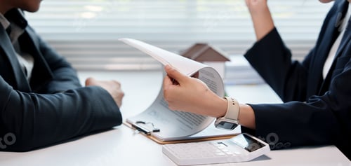Preview: Real estate agent showing a house contract to her client during a meeting in the office, with a mini
