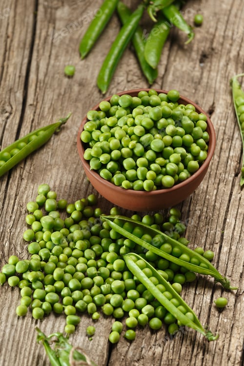 Preview: Green peas in closed and open pods, peeled peas in a bowl, pea seeds on a wooden background.