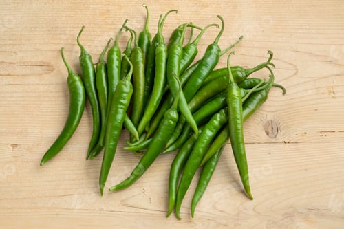 Preview: Group of fresh green chili peppers on wood