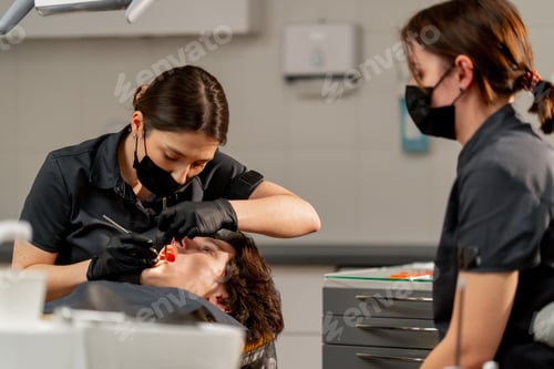Preview: in the dental office girl doctor examines the oral cavity using a mirror and a machine with air