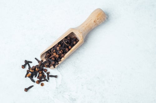 Preview: Cloves in a wooden scoop on a light background in a kitchen setting