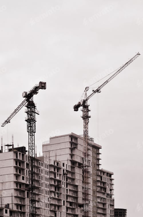 Preview: Working tall cranes inside place for with tall buildings under construction against a clear blue