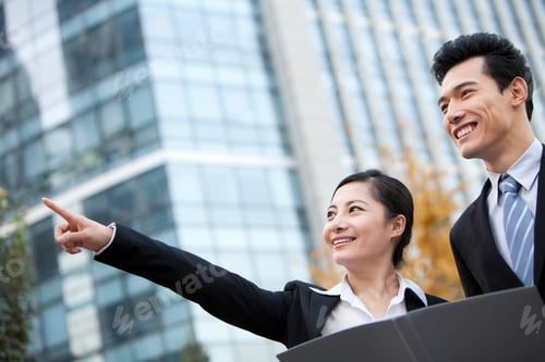 Preview: A businessman and businesswoman outside office buildings with a document planning