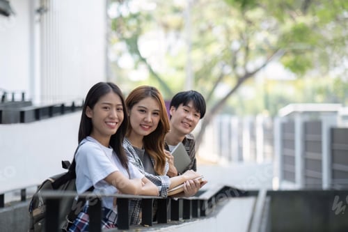 Preview: Group of young Asian college students sitting on in front of the school building, talking and