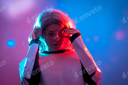 Preview: Beautiful woman putting on the futuristic glasses on a dark background, future and virtual reality