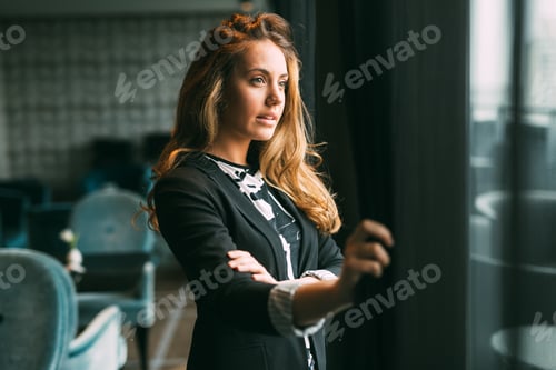 Preview: Pensive beautiful businesswoman looking through window