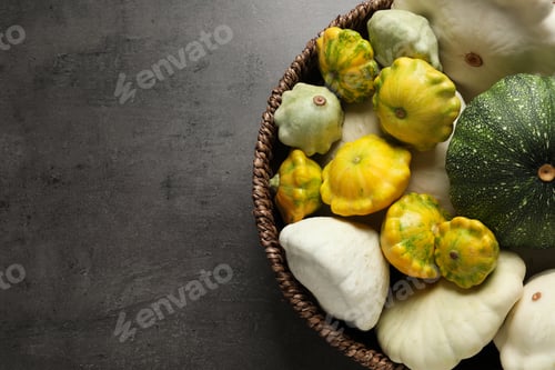 Preview: Fresh ripe pattypan squashes in wicker bowl on grey table, top view. Space for text
